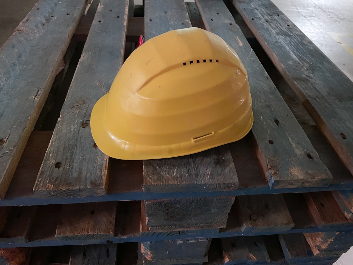 Yellow hard hat and industrial PPE on a wooden pallet